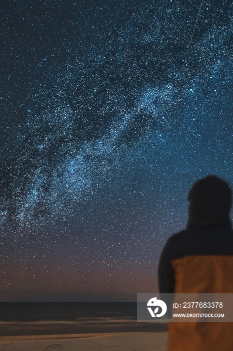 A silhouette of a person in front of a universe constellation. Concept of outdoors night skies and Milky Way observation.