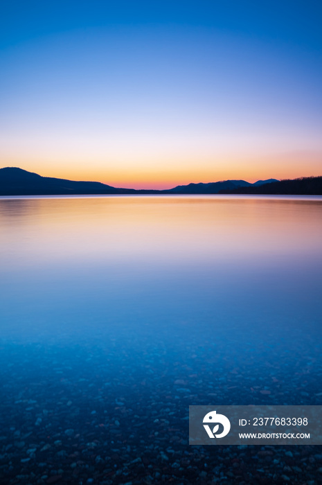 美しいグラデーションの空を反射する湖の風景。