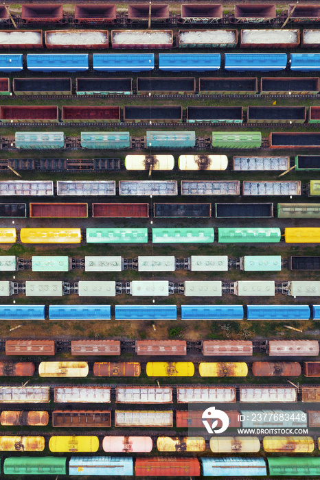 Aerial view of freight trains on the railway station. Cargo trains close-up. Wagons with goods on railroad. Industrial conceptual scene with trains. Top view.