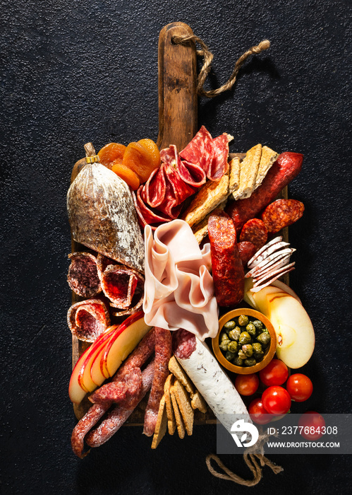 Assortment of salami and snacks. Sausage Fouet, sausages, salami, paperoni. On a black wooden background. Top view. Free space for your text