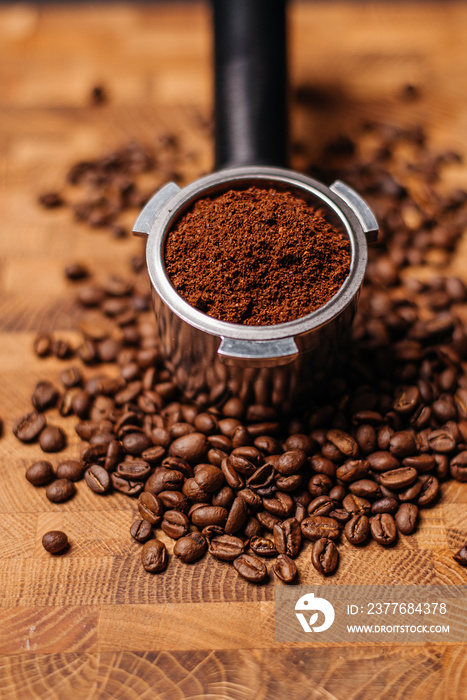 Portafilter with ground coffee on the background of coffee beans