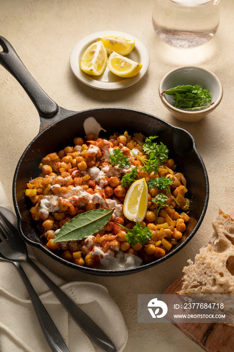 Cooked chickpea in frying pan with curry and spices, homemade vegan chickpeas, healthy food, neutral warm background