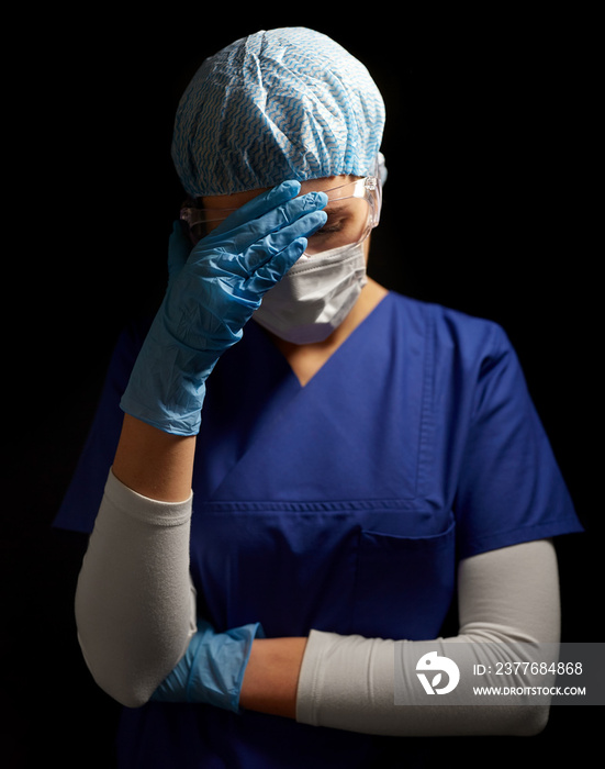 health, medicine and pandemic concept - sad young female doctor or nurse wearing goggles, hat and face protective mask for protection from virus disease over black background