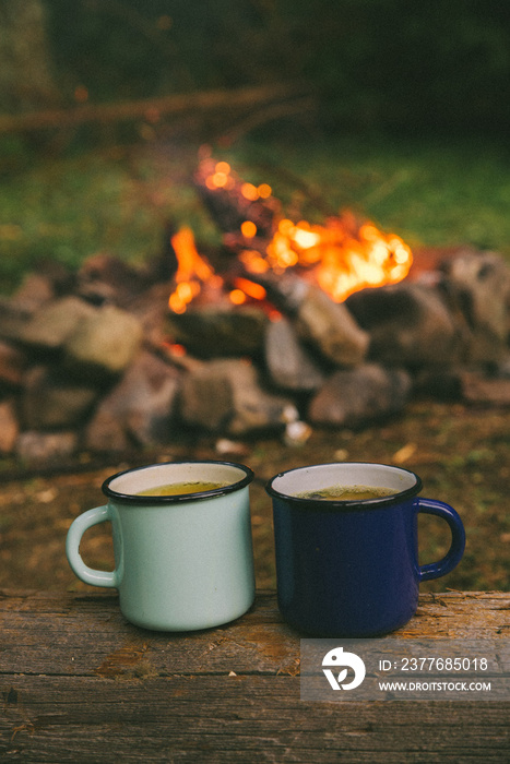 two metal cups with tea. fire on background