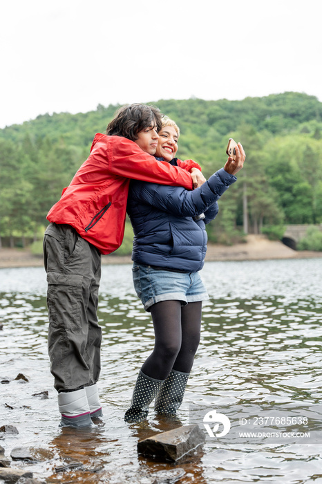 Mother and son wading in lake and taking selfie