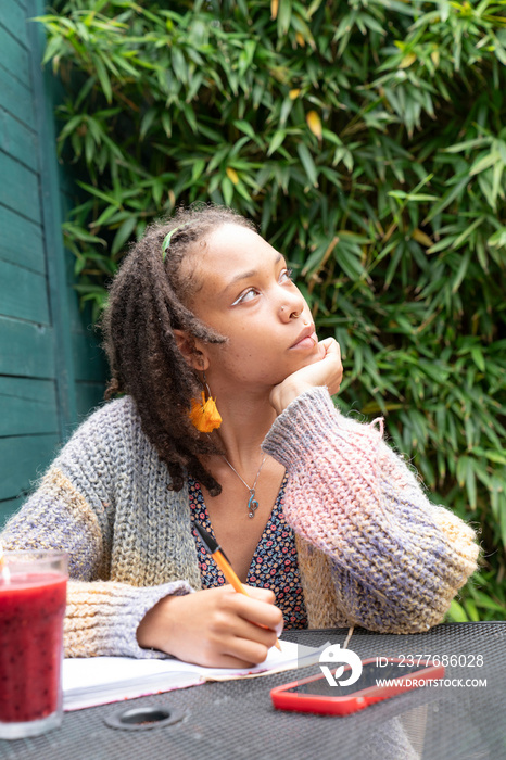 Young woman writing diary in garden