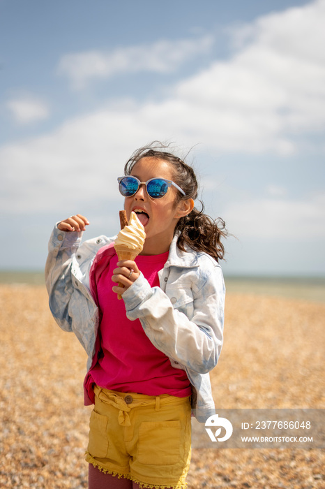 Girl (8-9) eating ice cream on beach