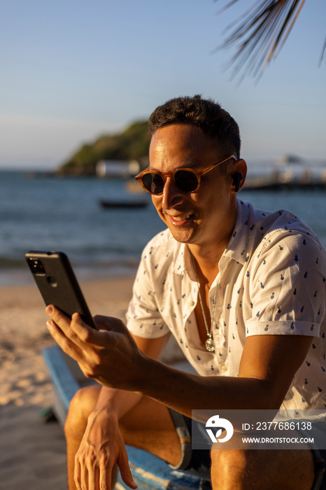 Man sitting on beach and using smart phone