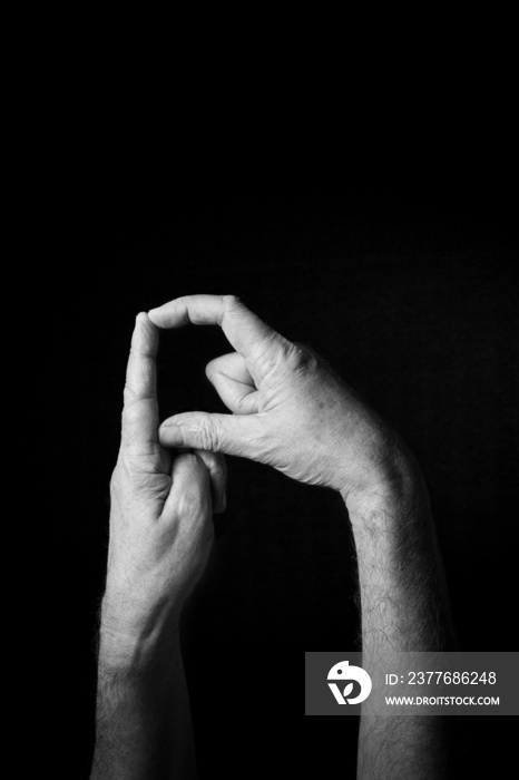 B+W image of hand demonstrating BSL sign language letter D isolated against black background