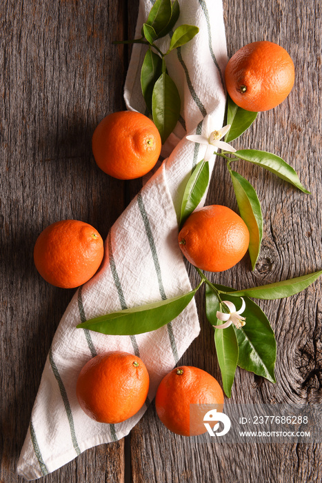 Closeup of a group of 6 tangelos with a towel and leaves on a rustic wood table