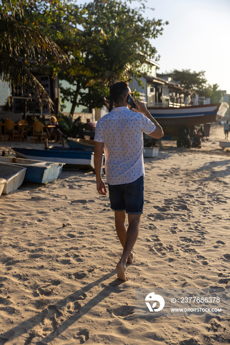 Man walking along beach and talking on phone