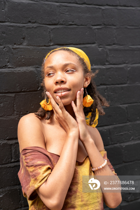 Portrait of young woman standing against brick wall