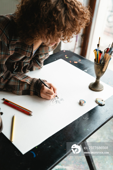 Smiling young redhead woman artist drawing