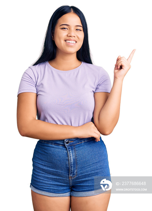 Young beautiful asian girl wearing casual clothes smiling happy pointing with hand and finger to the side
