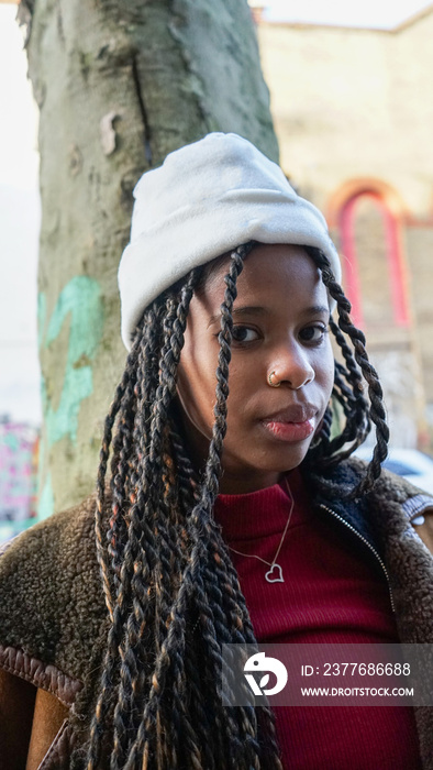 Portrait of young woman with braided hair and cap outdoors