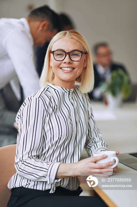 Smiling young businesswoman drinking a coffee in an office