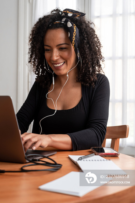 Shot of young latin woman working at home with laptop and documents