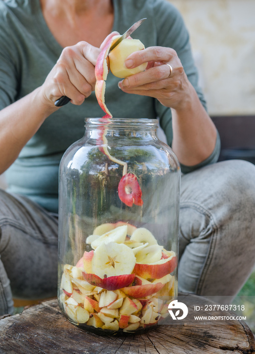 Woman makes apple vinegar - peeling apple and cut it into a bottle