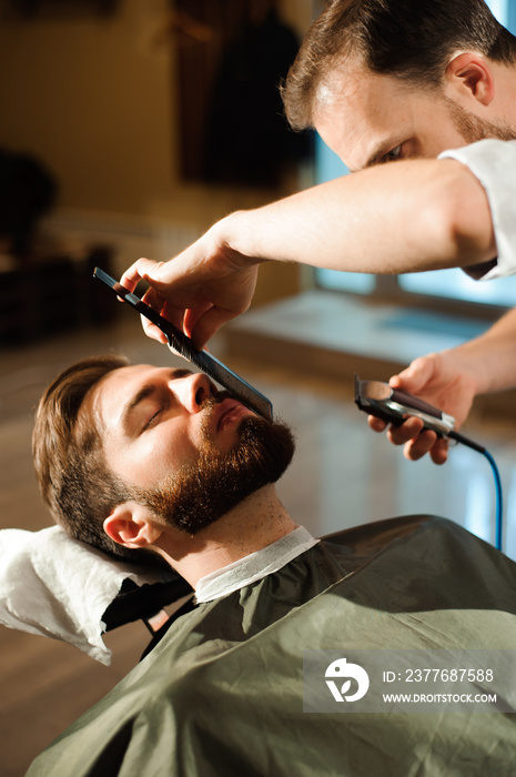 Master cuts hair and beard of men in the barbershop