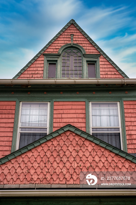 A unique old house in Binghamton NY.  Red shingles on a three-story house with blue skies and white clouds in Binghamton in Upstate NY.