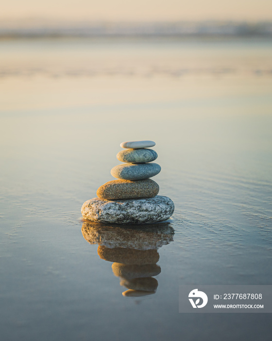 Pyramid of stones on the beach at sunset. Tranquil scene, relaxation, seaside vacation, meditation concept, copy space