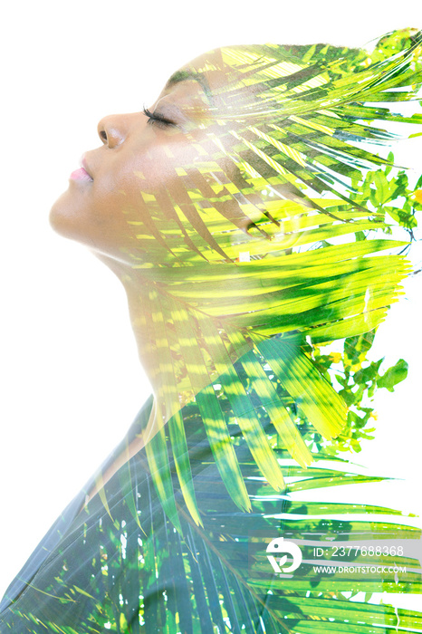 A profile portrait of a woman combined with tropical leaves in a double exposure technique.