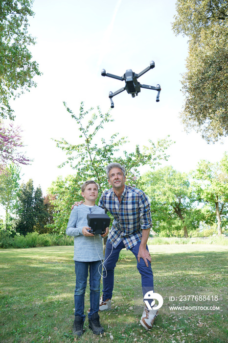 Father and son playing with flying drone in garden