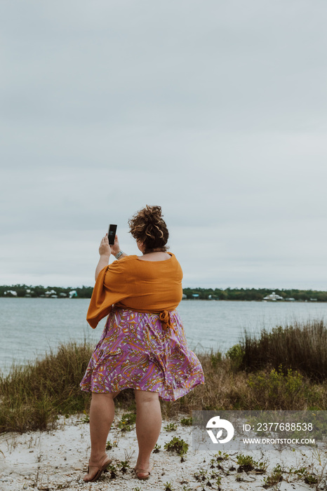 plus size woman takes photo of beach