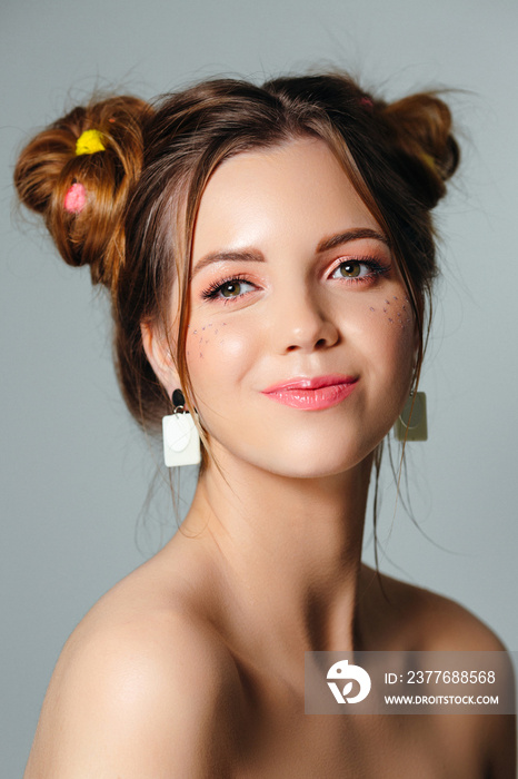 Young beautiful woman blowing bubble gum. Playful portrait of a girl with buns hairstyle. Cheerful summer girl.