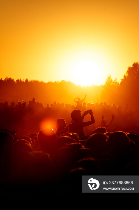 Crowd dancing on the summer party. Low sun orange light.