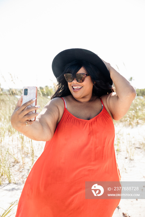 Plus size black woman wearing a hat takes a selfie