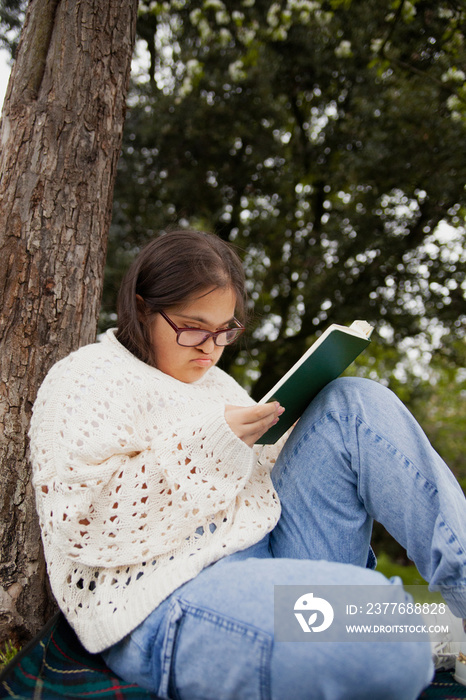 Curvy woman with Down syndrome reading in the park