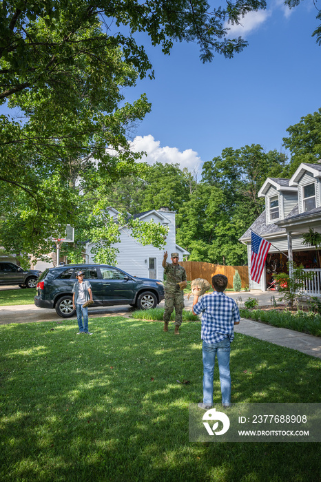 Air Force service member plays catch with sons after coming home from work in uniform.