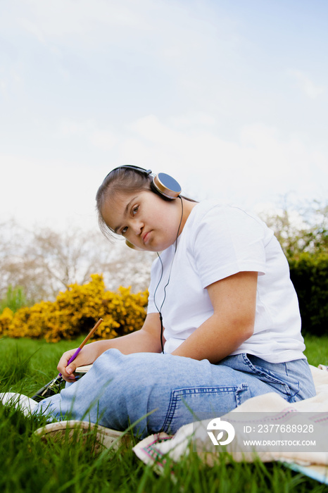 Young mid-sized woman with Down Syndrome listening to music in the park