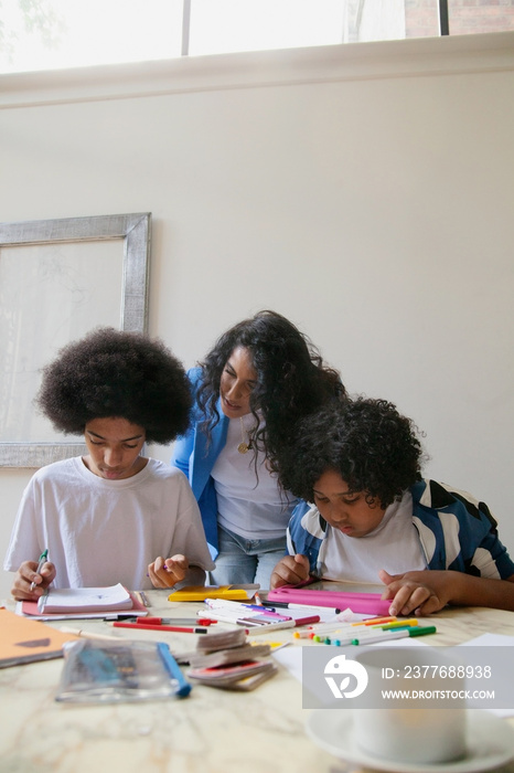 Mid-sized mother helping her children with homework and drinking coffee