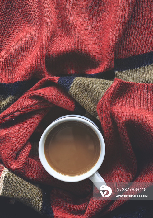 winter concept. cup of coffee on red sweater background. over light and vintage tone