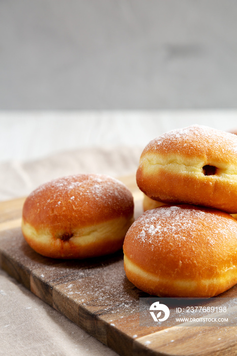 Homemade Apricot Polish Paczki Donut with Powdered Sugar on a Wooden Board, low angle view. Close-up.