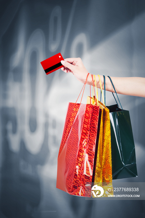 Unknown woman holds credit card and shopping bags