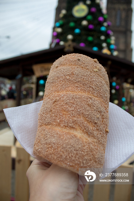 Trdelník is a kind of spit cake, made from rolled dough that is wrapped around a stick, then grilled and topped with sugar and walnut mix. National food in the Prague Christmas market.