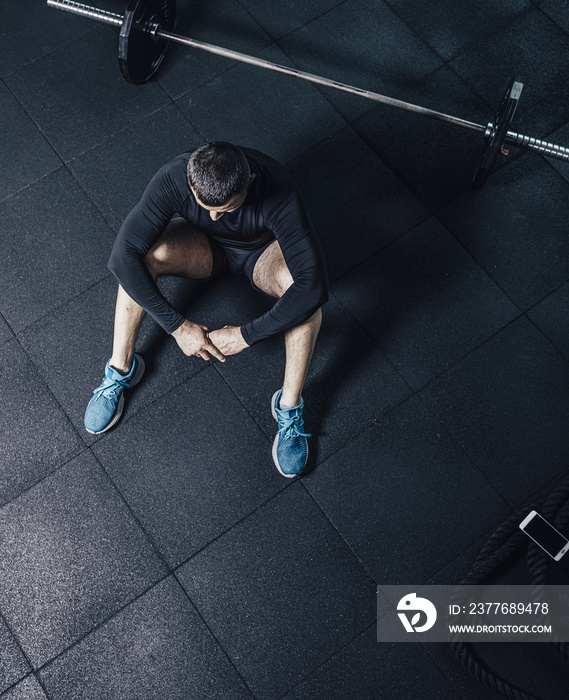 Young bearded man resting after workout. Healthy young male taking break after training in gym.