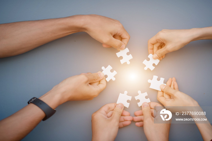 The hand of a businessman holding a paper jigsaw And solve the puzzle together. The business team assembled a jigsaw puzzle. A business group wishing to bring together the puzzle pieces