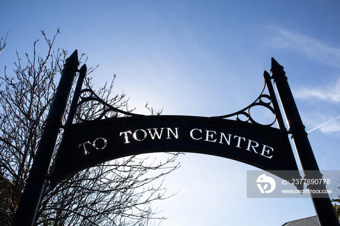 To Town Centre urban sign in decorative metal with tree and sky background