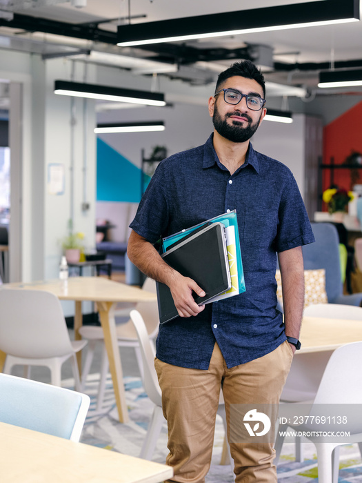 Portrait of man holding laptop in office