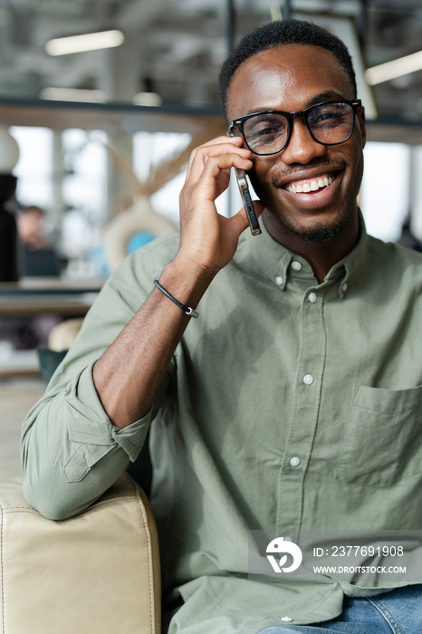 Young man with smartphone sitting in office lounge