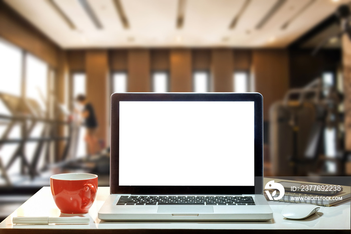 Front view of cup and laptop on table in Office in fitness gym in morning light