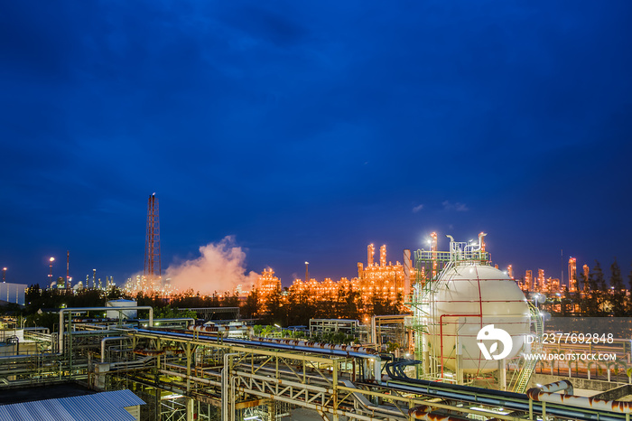 Gas storage sphere tanks and pipeline in oil and gas refinery industrial plant with glitter lighting industry estate at twilight