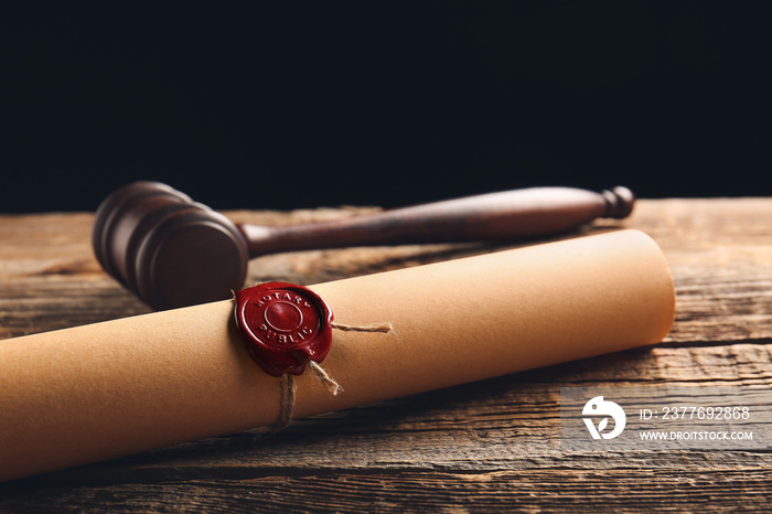 Scroll with notary public wax seal and gavel on table