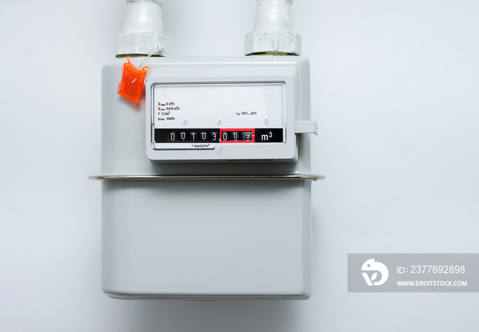 A gas meter on the white wall. Counter for distribution natural gas.