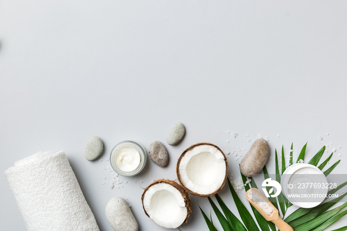 Coconut with jars of coconut oil and cosmetic cream on colored background. Top view. Free space for your text. Natural spa coconut cosmetics and organic treatment concept Coconut Spa composition