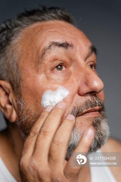 Portrait of man applying cream on face